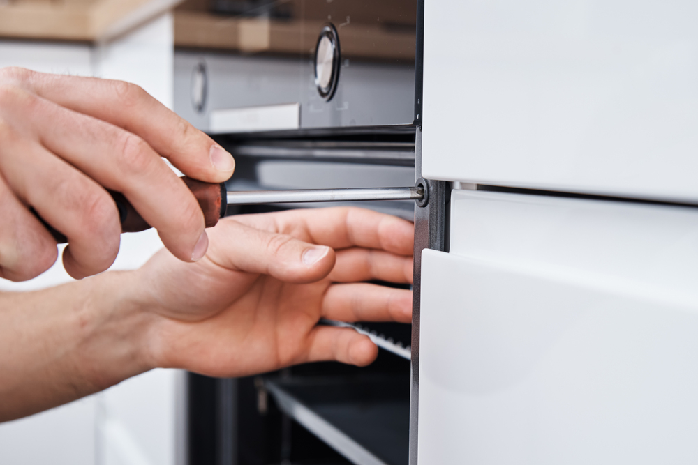 oven repair engineer installing an oven in the kitchen